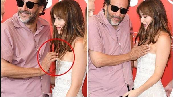 Dakota Johnson looks uncomfortable as the film director touches her breast